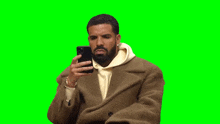 a man in a brown coat is taking a selfie with his cell phone .