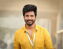 a man in a yellow shirt with a blue lanyard around his neck smiles