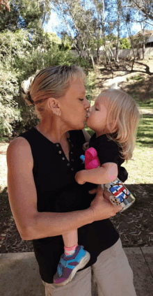 a woman is kissing a little girl who is wearing a bottle that says ' spiderman ' on it