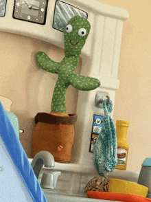 a stuffed cactus with googly eyes is sitting on a kitchen counter