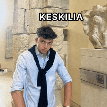 a young man stands in front of a stone wall with the word keskilia on the bottom