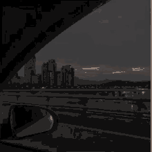 a car driving down a highway at night with a city in the background