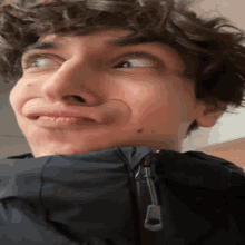 a young man with curly hair is making a funny face with his mouth open