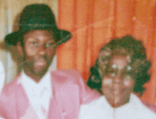 a man in a pink suit and a woman in a white shirt pose for a picture