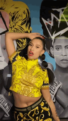 a woman wearing a yellow top and black skirt with a versace logo on the bottom