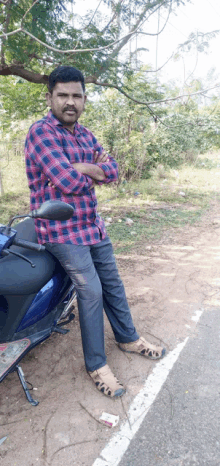 a man in a plaid shirt leans on a motorcycle