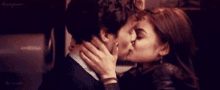 a man and a woman are kissing in a dark room in a close up .