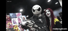 a man dressed as jack skellington and a woman dressed as sally pose for a picture at a convention .