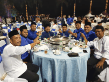 a group of men are sitting at a table with a blue tablecloth