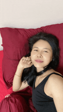 a woman in a black tank top is laying on a bed