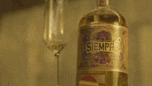 a bottle of siempre tequila sits next to a wine glass