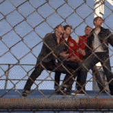 a group of men behind a chain link fence with one wearing a red jacket that says ' chicago ' on it