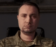 a man in a military uniform is sitting in a chair and looking at the camera with a serious look on his face .