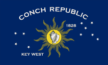 a flag for conch republic key west with a sun and a shell