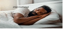 a man with a beard is sleeping on a bed with white sheets and pillows .