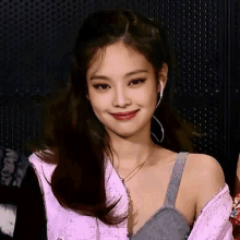 a woman wearing ear buds and a pink shirt smiles for the camera