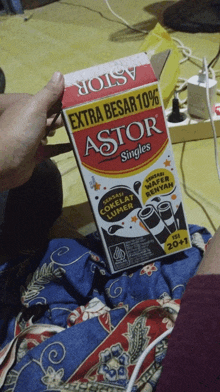 someone is holding a box of astor singles