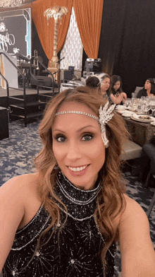 a woman wearing a headband and a black dress is smiling