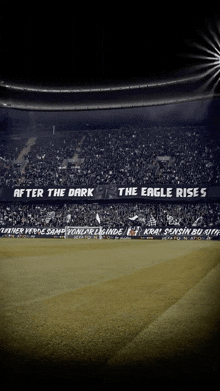 a black and white photo of a soccer stadium with a banner that says after the dark the eagle rises