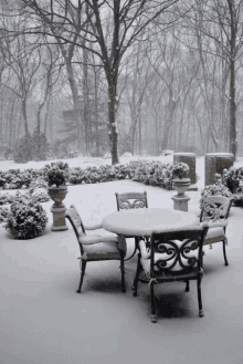 a table and chairs are covered in snow on a snowy day