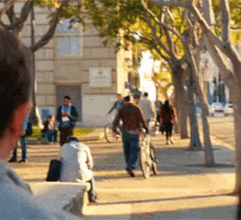 a group of people are walking down a sidewalk in front of a building with a clock on the side