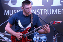 a man playing a red guitar in front of a sign that says music instruments