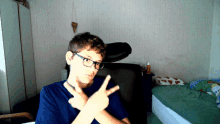 a boy wearing glasses is making a peace sign with his hands