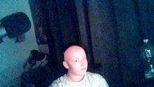 a man with a bald head is sitting in front of a dark room