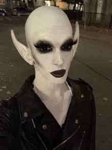 a person wearing a black leather jacket and white makeup looks like an alien