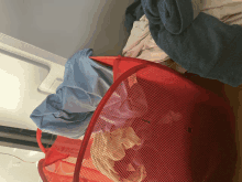 a red laundry basket filled with clothes including a blue blanket