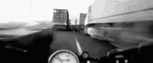 a black and white photo of a person riding a motorcycle on a highway with a clock on the dashboard .