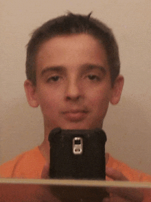 a young boy is taking a selfie with a black cell phone