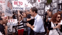 a man is standing in front of a crowd holding a sign that says ' beto for everyone ' .