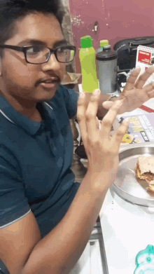 a man wearing glasses is sitting at a table with a plate of food and a sign that says subway