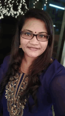 a woman wearing glasses and a nose ring smiles for a selfie