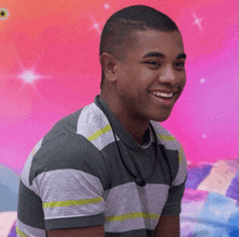 a young man wearing a striped shirt is smiling with a pink background