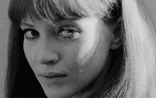 a black and white photo of a woman 's face with long hair and a fringe .