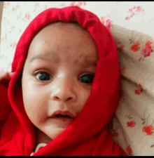 a baby is wearing a red hooded sweatshirt