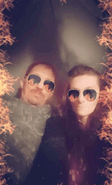 a man and a woman wearing sunglasses in front of a fire frame