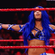 a woman with blue hair is standing in a wrestling ring ..