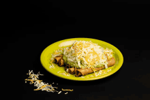 a green plate with tacos and guacamole on it