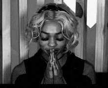 a woman with blonde hair is praying with her eyes closed