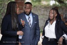 a man in a suit and tie is talking to two women next to the words next definition media photography