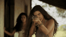 a woman with long hair is pointing a gun at something