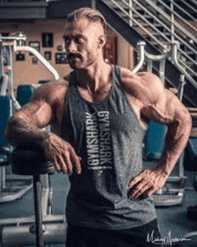 a man is leaning against a bench in a gym .