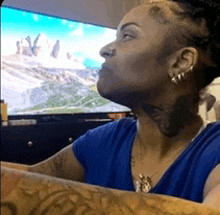 a woman with tattoos on her neck is sitting in front of a tv .