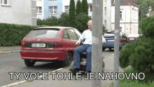 a man sits on a scooter in front of a red car with a license plate that says pub 5585