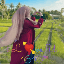 a woman in a hijab is making a heart shape with her hands in front of a field with the words love you written on it