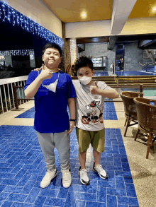 two boys wearing face masks pose for a photo