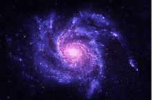 a purple and blue spiral galaxy in the middle of a galaxy in space .